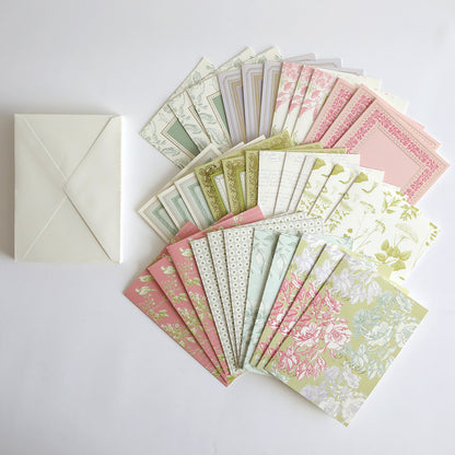 A selection from the Beautiful Botanical Bundle—featuring floral and patterned stationery papers—fans out beside a single cream-colored envelope on a white background, making it ideal for layered card making or pairing with antique botanical rub on transfers.