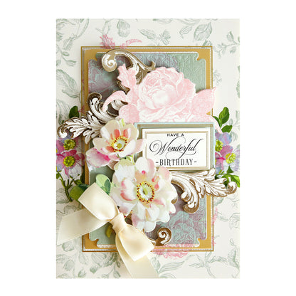 A decorative birthday card designed with the Beautiful Botanical Bundle, featuring floral patterns, layered paper flowers, gold accents, a cream ribbon bow, and accented with antique botanical rub on transfers. The card reads: “Have a Wonderful Birthday.”.