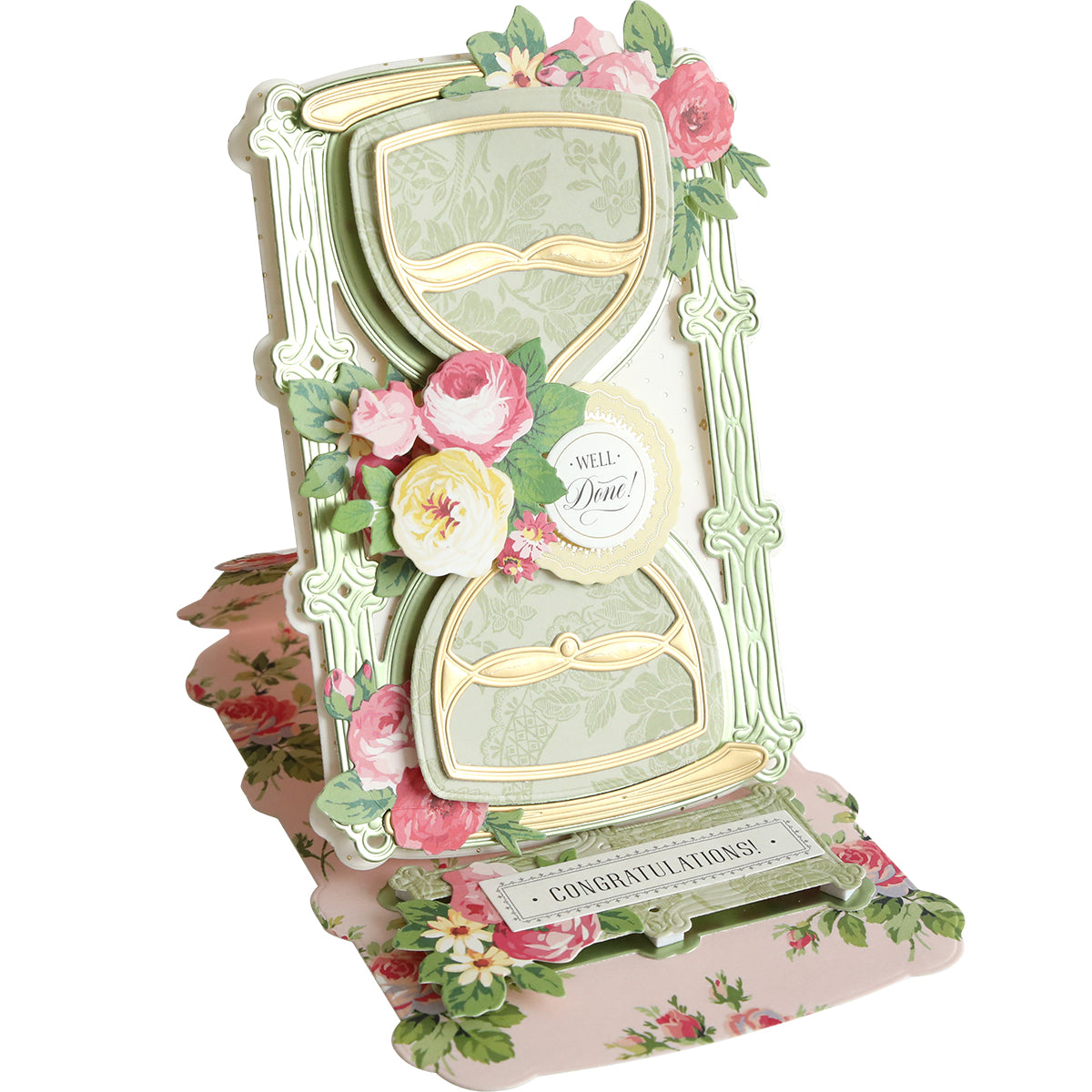 A decorative pop-up shaker card made with 3D Hour Glass Dies, featuring an ornate hourglass with pink and yellow flowers, a “Well Done!” message, and “Congratulations!” on a floral background.