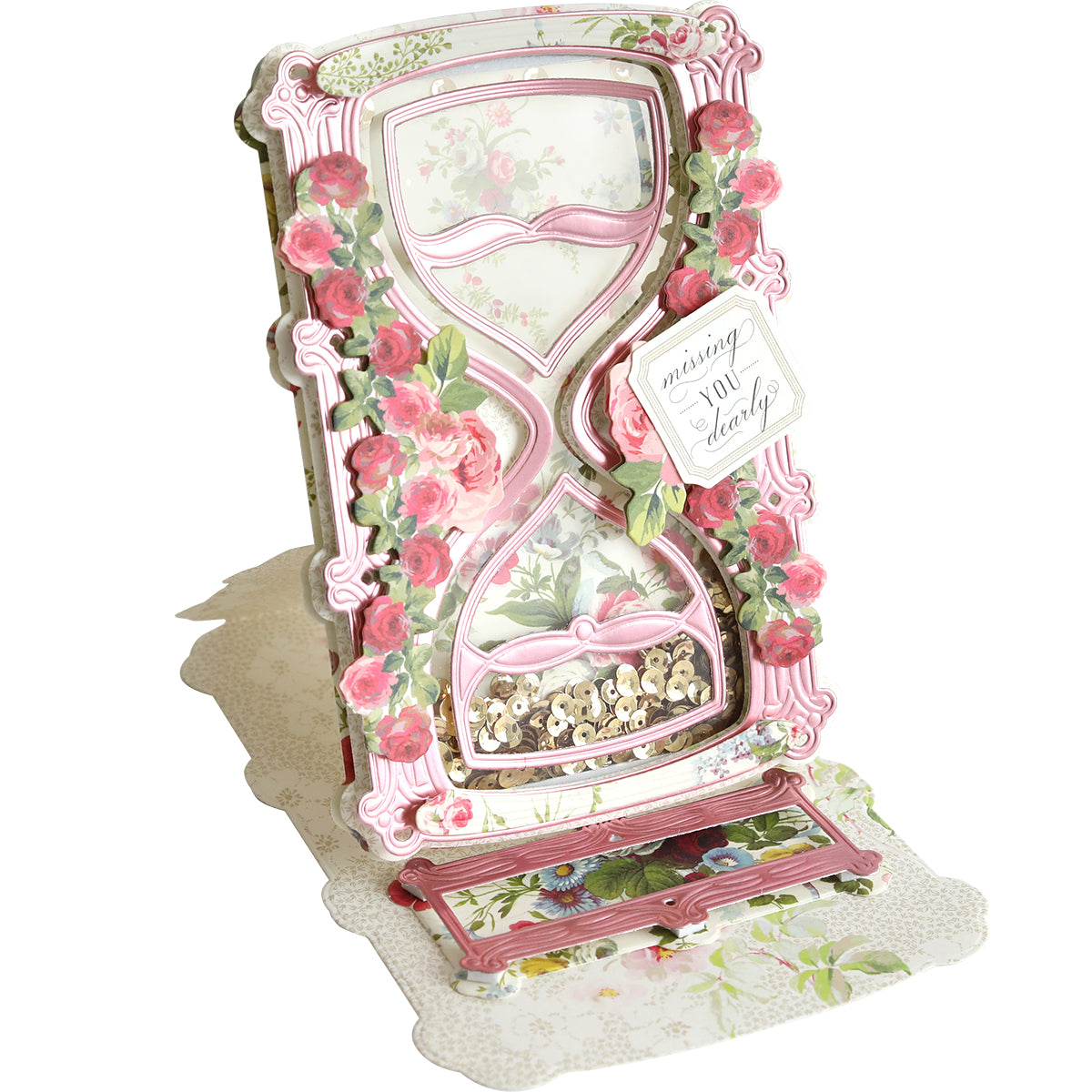 A decorative, floral shaker card featuring 3D Hour Glass Dies, pink roses, a "missing you dearly" tag, and sparkling sequins in the lower hourglass for extra charm.