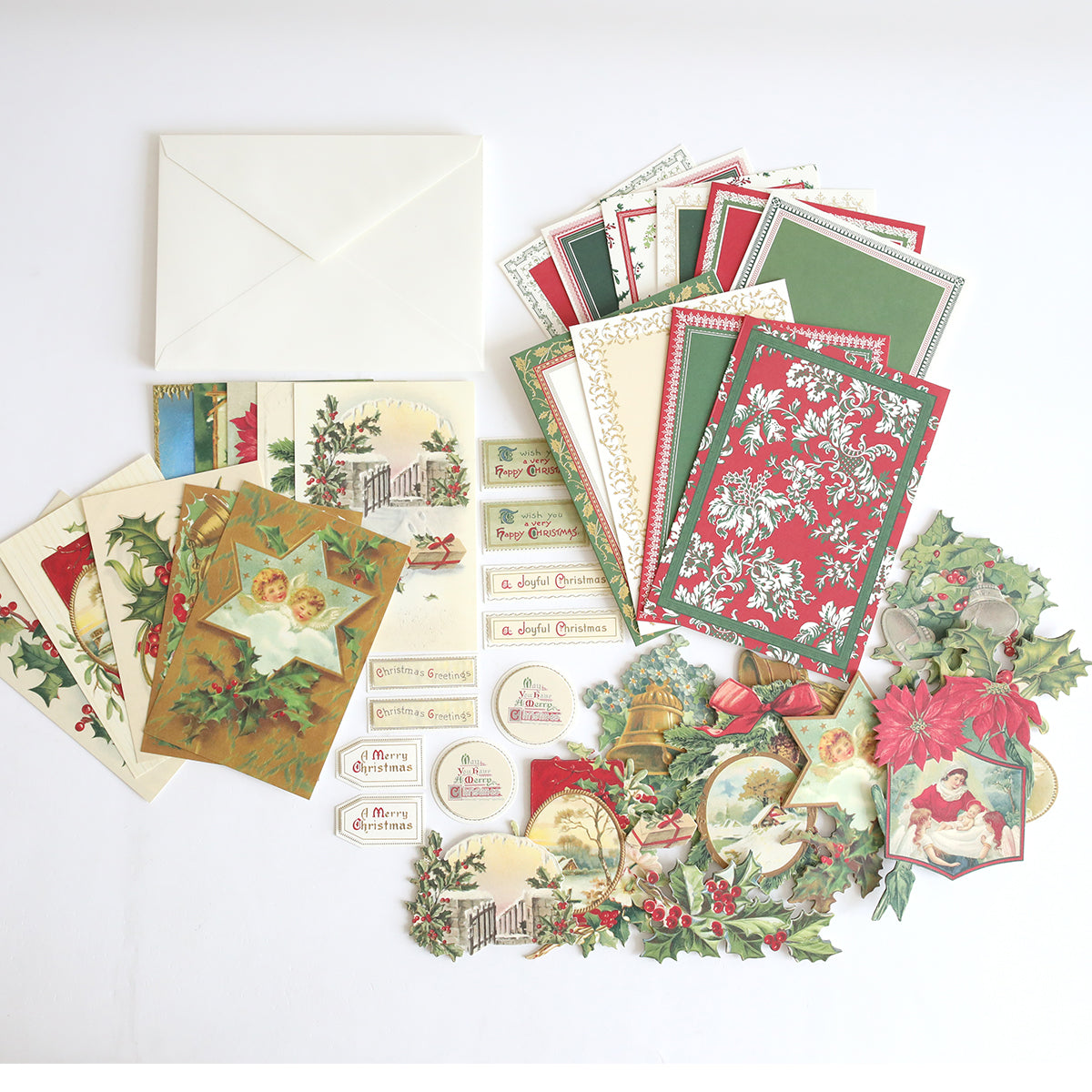 The Christmas Postcard Card Making Kit features holiday greeting cards, envelopes, decorated tags, festive die-cut paper pieces, and vintage-style postcards—all with Christmas motifs on a white background.