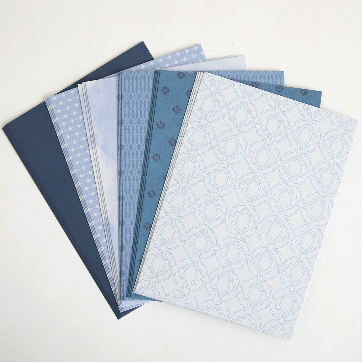 Six Color Drenched Cardstock French Blue sheets with geometric and patterned blue-toned designs are fanned out on a white background—ideal for card making or pairing with your favorite double-sided cardstock projects.