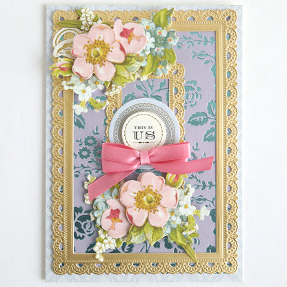 Decorative greeting card featuring pink flowers, gold foil lace borders, a pink bow, and a "This Is Us" label on a patterned lavender background made with Color Drenched Cardstock French Blue—perfect for card making enthusiasts.