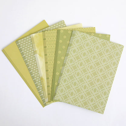 A set of six Color Drenched Cardstock Sage Green papers, featuring assorted green and yellow geometric and floral designs, fanned out on a white background—ideal for card making.