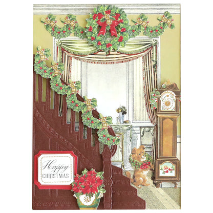 A cozy living room scene showcases a staircase adorned with the Grand Staircase Dies and Embellishments, garlands, a festive wreath, and poinsettias. The decor includes an elegant "Happy Christmas" sign, a grandfather clock by which a dog sits, all creating a warm holiday atmosphere.