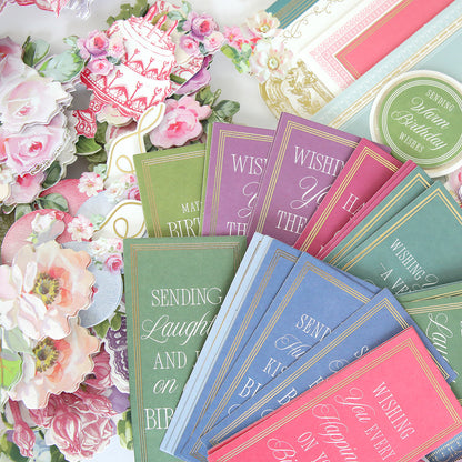 An assortment of floral and pastel-toned handmade birthday cards and decorative paper pieces from the Birthday Present Card Making Kit are arranged on a white surface.