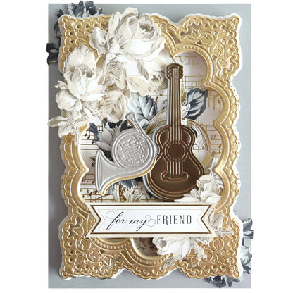 A decorative card made with Music 3D Scene Dies, featuring gold borders, white flowers, a French horn, guitar, musical accents, and finished with a "for my FRIEND" banner.