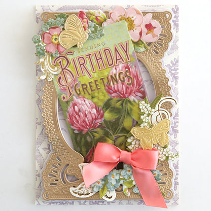 A decorative birthday card with pink flowers, gold accents, butterflies, and a pink ribbon bow on a layered frame—perfect for pairing with Antique Birthday Postcard Embellishment Stickers.