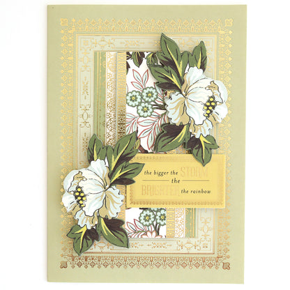 Greeting card adorned with white flowers, lush green leaves, and elegant gold borders—ideal for layered card projects or coordinating with the Beautiful Botanical Bundle’s antique botanical rub on transfers. The central message reads: “the bigger the storm the brighter the rainbow.”.