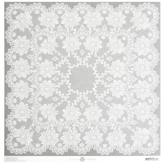 Introducing the Endora Grey Lace 12x12 Cardstock: a square lace doily with an intricate floral pattern set against a plain background. The design features detailed, delicate lacework and a central circular motif. Ideally suited for pairing with single-sided 12″ x 12″ patterned cardstock to create stunning craft projects.