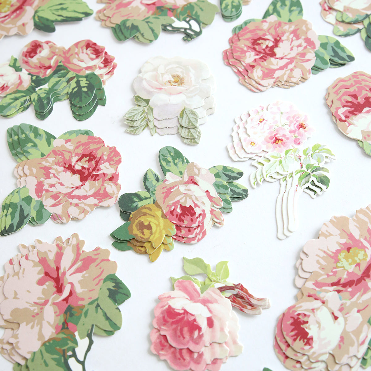 Virginia Die Cut Embellishments feature pink, white, and yellow flowers with green leaves—perfect for adding charm to scrapbooks when arranged on a white surface.