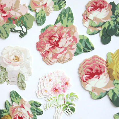 Several stacks of Virginia Die Cut Embellishments, featuring floral stickers—mainly pink, white, and green roses—are arranged on a white background, perfect for use as scrapbook embellishments.