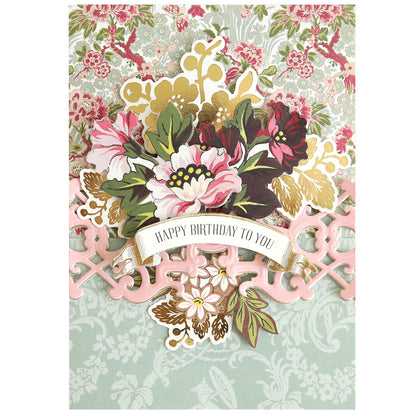 Birthday card featuring a bouquet illustration and a banner that reads “Happy Birthday To You,” designed with the 12″ Regal Trimmings Border Dies and accented with rose gold matte foil cardstock on a patterned floral background.
