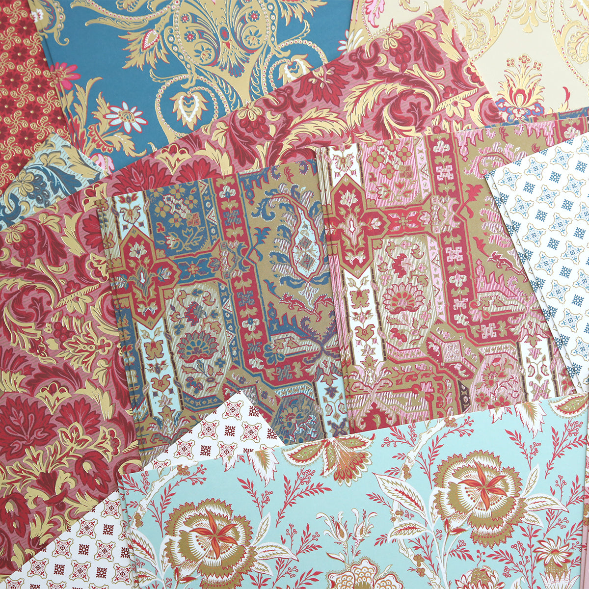 Overlapping fabric samples in red, blue, beige, and gold evoke the sophisticated patterns of the Jasmine Cardstock Collection.