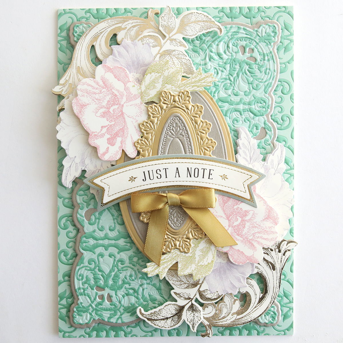 The Jasmine Luxury Tonal Foil Cardstock is a decorative green embossed card with floral designs, an ornate frame, gold foil details, a ribbon, and a “JUST A NOTE” banner—ideal for crafting elegant handmade greetings.