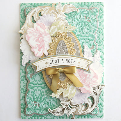 The Jasmine Luxury Tonal Foil Cardstock is a decorative green embossed card with floral designs, an ornate frame, gold foil details, a ribbon, and a “JUST A NOTE” banner—ideal for crafting elegant handmade greetings.