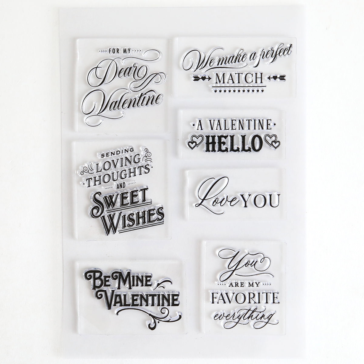 The Lovely Sentiment Stamps set includes seven clear stamps with romantic phrases like "Love You" and "Be Mine Valentine," perfect for decorating scrapbook pages or making heartfelt handmade cards.