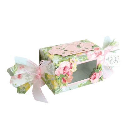 A floral favor box with a clear window, pink ribbon ends, and rose accents—perfect as a treat box crafted with the Candy Wrapper Box Dies.
