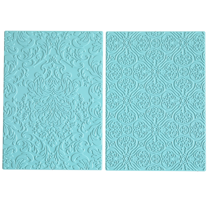Two light blue silicone mats, inspired by damask designs, are placed side by side on a white background. These mats coordinate with the Gilded Damask Hot Foil Plates and are ideal for use with embossing machines.