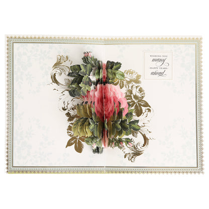 The Folded Rose Card Making Kit includes an open greeting card featuring a three-dimensional pink flower with green leaves as the centerpiece, gold decorative accents, and the message "Wishing you many happy years ahead." Ideal for showcasing your favorite 3D embellishments or for use with a floral card making kit, this set brings elegance and charm to any special occasion.