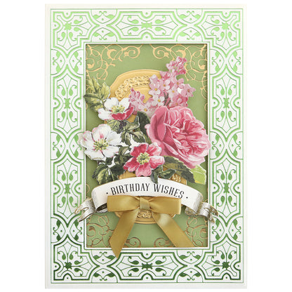 A greeting card with "Birthday Wishes," pink and white flowers, gold accents made with Gilded Ironwork Frames Hot Foil Plates, and a gold ribbon on a green decorative background.