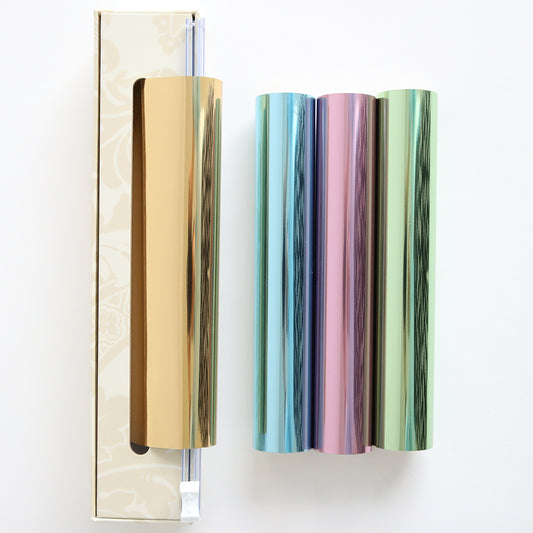 The Perfect Palette Pastel Gild Hot Foil includes three metallic rolls in gold, blue, and pink-green, packaged in a gold-patterned box—ideal for adding shimmer to paper crafts.