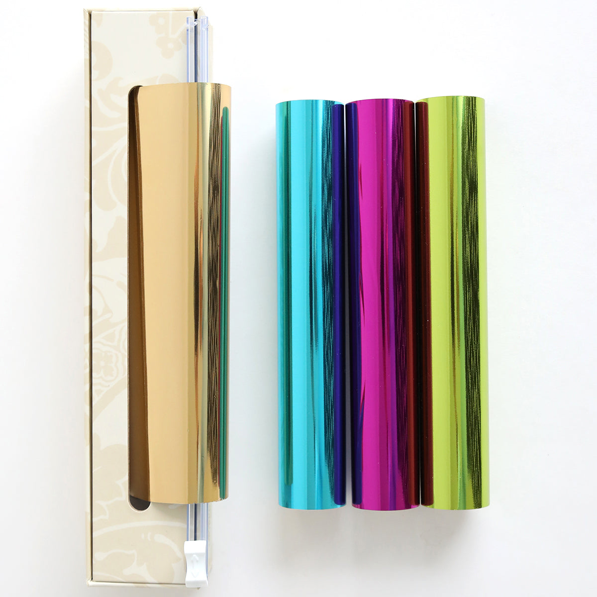 Four Perfect Palette Bright Gild Hot Foil rolls in gold, blue, purple, and green stand vertically on a white surface, with one roll partially inside a beige box.