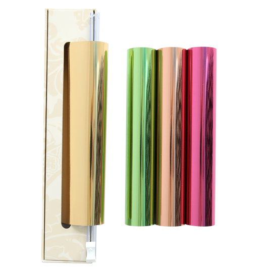 Four metallic foil rolls in shiny gold, green, orange, and pink stand upright next to a box with a sliding cutter on a white background. The Perfect Palette Antique Gild Hot Foil set is perfect for adding eye-catching accents to your crafts, just like those created with the Anna Griffin Gild Hot Foil system.