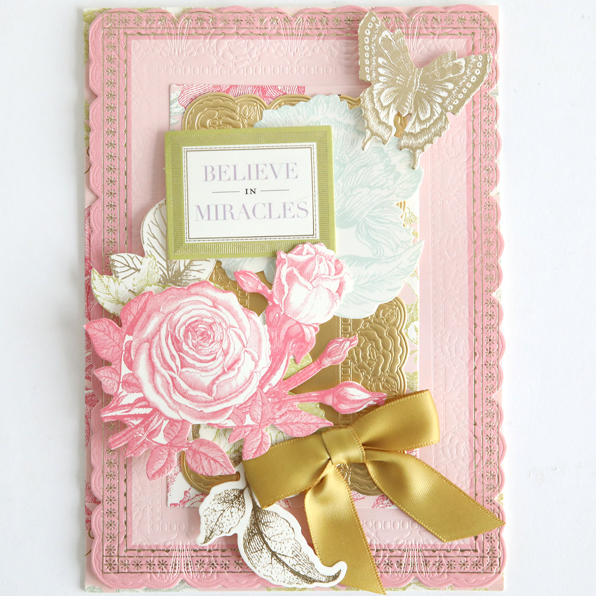 The Card Layer Photo Mat Bundle is a decorative greeting card set for cardmaking, featuring pink florals, a gold bow, butterfly artwork, and the message "Believe in Miracles" on the front.
