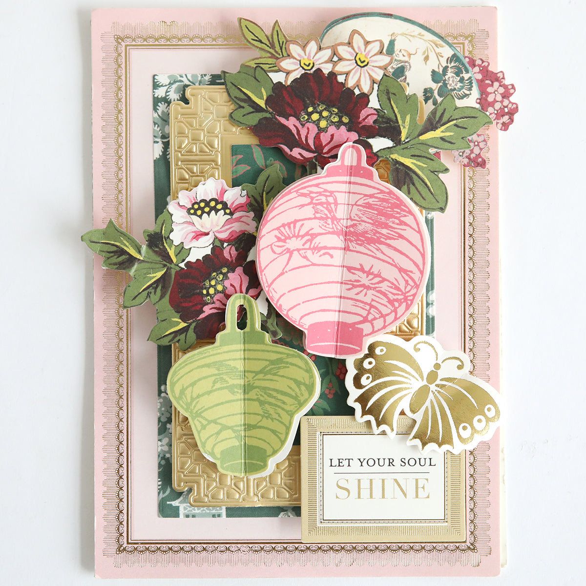 The Card Layer Photo Mat Bundle is perfect for scrapbooking or cardmaking, featuring layered floral designs, paper lantern cutouts, and a "LET YOUR SOUL SHINE" plaque on a pastel background.