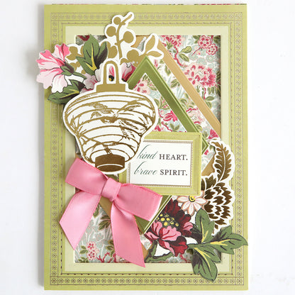The Card Layer Photo Mat Bundle includes a handmade greeting card with floral patterns, a gold lantern, and "kind heart. brave spirit." message—ideal for cardmaking or scrapbooking projects.