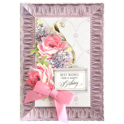 A decorative birthday card with pink and purple flowers, a gold accent, pink ribbon bow, and “Best wishes for a happy birthday” message, finished with Create Border, Frame and Shape Dies for added charm.