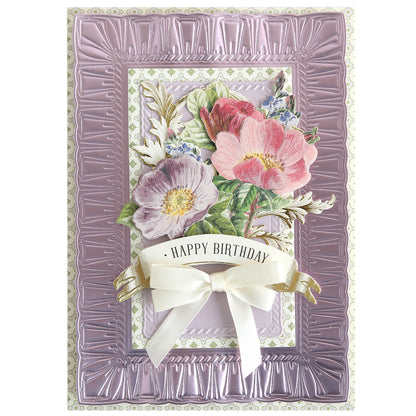 A decorative birthday card featuring embossed purple borders, floral designs, and a white ribbon bow with "Happy Birthday," crafted using Create Spring Frame Dies for an elegant touch.