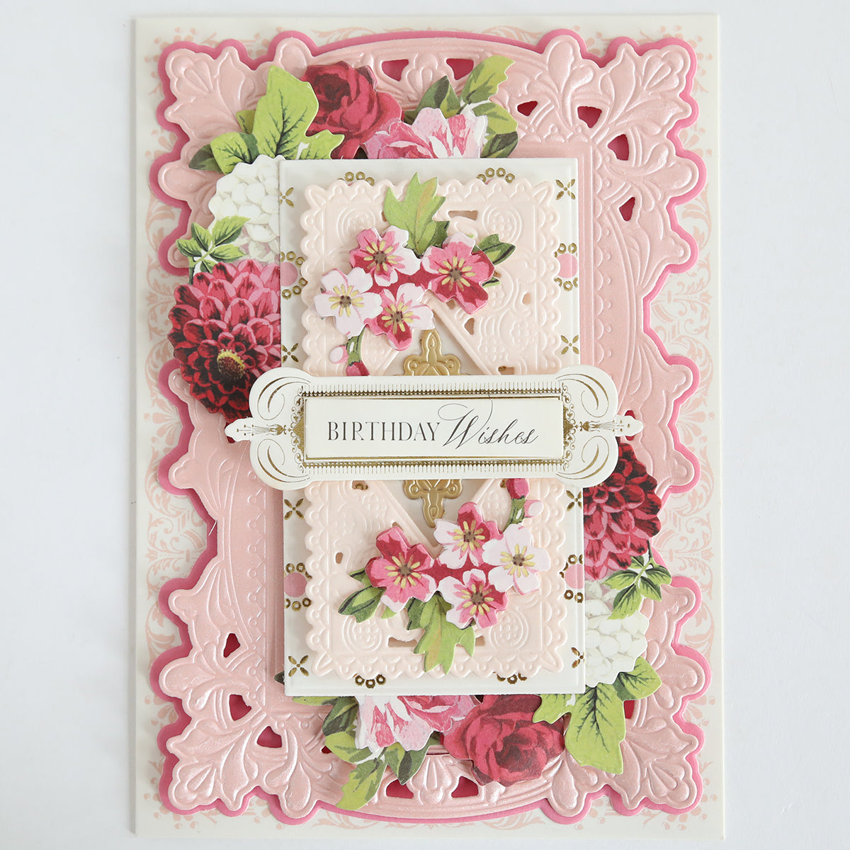 A decorative birthday card with layered pink and white embossed paper, pink floral designs, and a "Birthday Wishes" label, elegantly accented using the Lotus Concentric Frames 3D Die Set for a sophisticated papercraft finish.