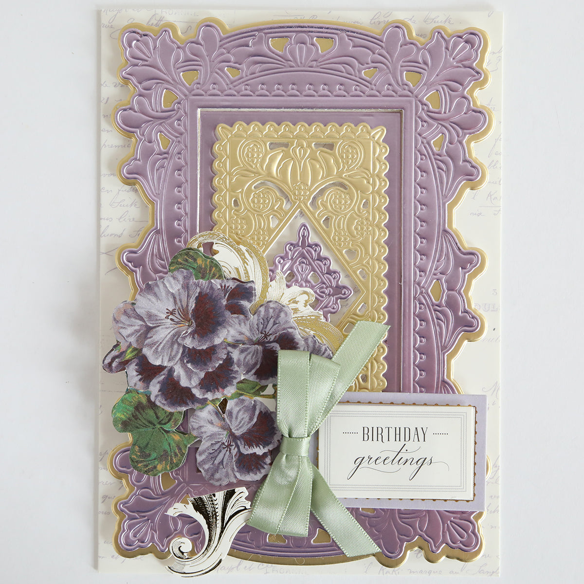 Greeting card featuring ornate gold and purple layered patterns, purple flowers, a green ribbon bow, and a "Birthday greetings" tag, beautifully crafted with the Lotus Concentric Frames 3D Die Set—ideal for any papercrafting project.