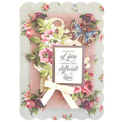 The Simply Sympathy Card Making Kit features floral and butterfly designs, a gold script background, and a white ribbon bow. Ideal for heartfelt handmade sympathy cards with the message: "Thinking of you during this difficult time.