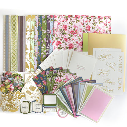 The In The Garden Ultimate Paper Crafting Kit features floral papers, patterned sheets, greeting cards, envelopes, gold sentiments, and embellishments—ideal for scrapbooking or any papercraft project.