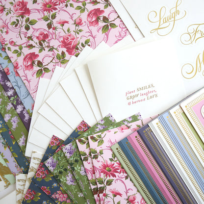 A selection of patterned and floral cards from the In The Garden Ultimate Paper Crafting Kit is fanned out, with one card showing: "plant SMILES, Grow laughter, & harvest LOVE." Perfect for cardmaking and papercrafting projects.