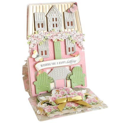 The Summer House 3D Easel Dies create a pop-up birthday card shaped like a pink house with flowers, butterflies, and green chairs—ideal for summer house crafting fans or anyone who loves the charm of a beach cottage card.