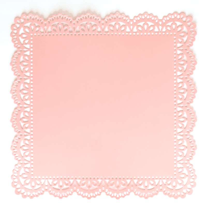 A pink paper doily on a white background.
