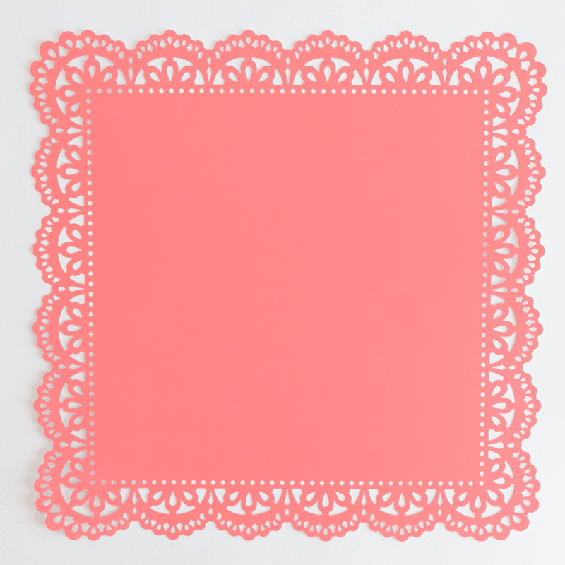 A pink paper doily on a white background.