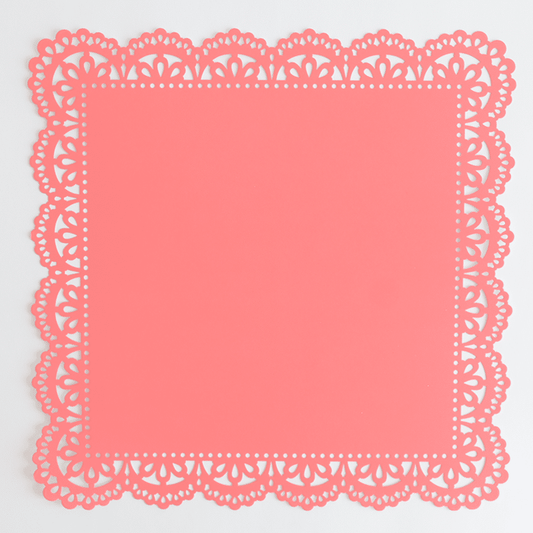 A pink paper doily on a white background.