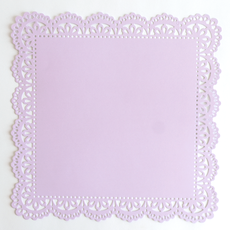 A purple paper doily on a white surface.