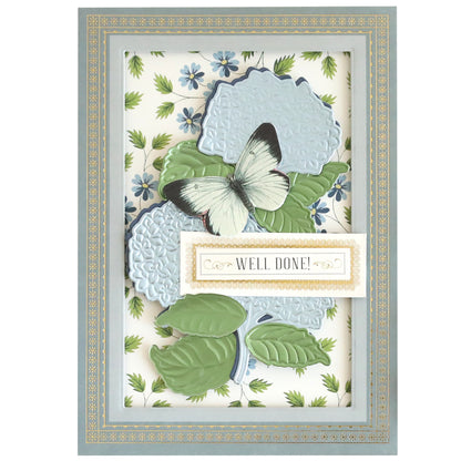 The Luxury Hydrangea Blue Matte Foil Cardstock features blooming hydrangeas, a butterfly, and green leaves with a gold-bordered "WELL DONE!" label on a floral background.