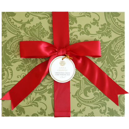A green patterned box with a large red ribbon and bow, featuring a round tag labeled "Christmas Grace Card Making Kit"—perfect for creating beautiful handmade Christmas cards with this festive holiday set.