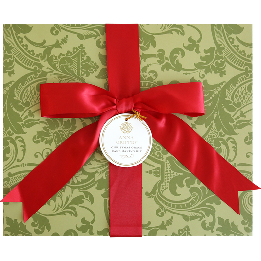 A green patterned box with a large red ribbon and bow, featuring a round tag labeled "Christmas Grace Card Making Kit"—perfect for creating beautiful handmade Christmas cards with this festive holiday set.