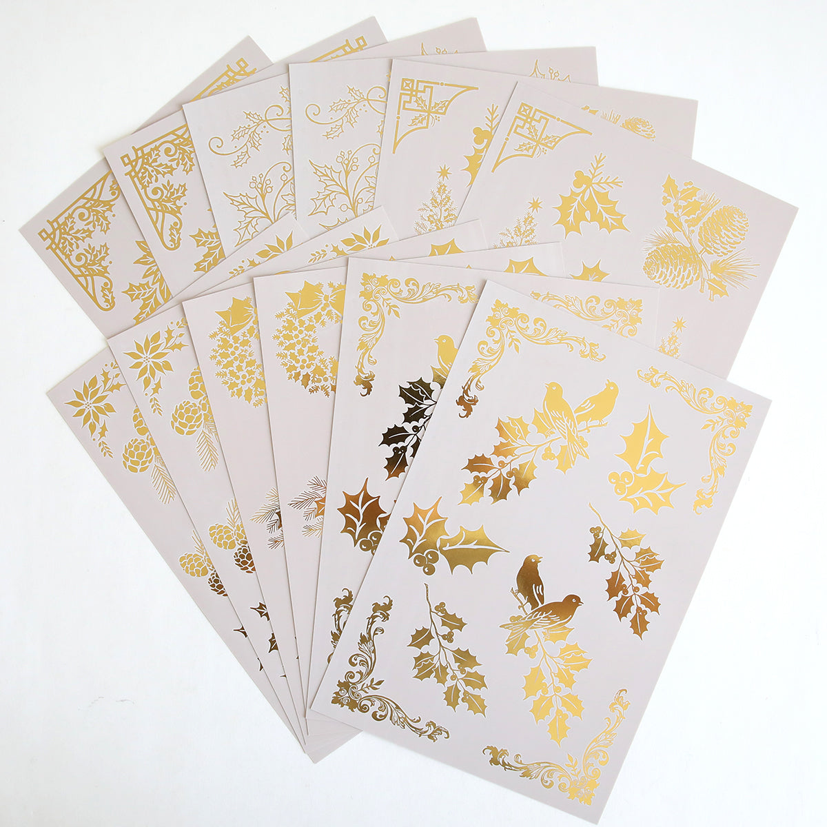 Holiday Nostalgia Foil Rub Ons includes 10 beige sheets with gold and metallic holiday designs—holly, birds, pinecones, and ornate patterns—ideal for adding vintage shimmer to your Christmas papercrafts.