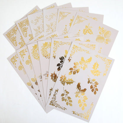 Holiday Nostalgia Foil Rub Ons includes 10 beige sheets with gold and metallic holiday designs—holly, birds, pinecones, and ornate patterns—ideal for adding vintage shimmer to your Christmas papercrafts.