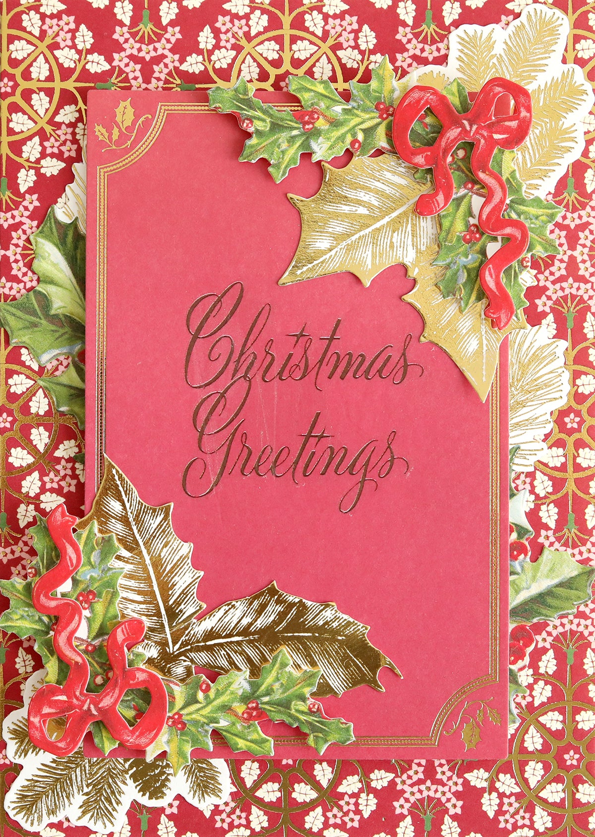A beautiful handmade card for holiday paper crafts enthusiasts showcases the Christmas Card Sentiment Rub Ons featuring "Christmas Greetings" in elegant script, accented with gold borders, holly leaves, and red ribbon decorations against a red and gold patterned background.