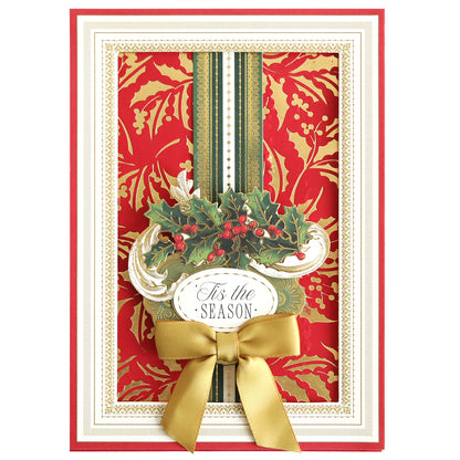A festive card adorned with a gold and red Christmas Holly pattern, accented by a green vertical stripe, gold ribbon bow, and “’Tis the Season” text in an ornate frame. The elegant foiled backgrounds are crafted using the Gilded Christmas Holly Hot Foil Plate for an extra touch of holiday sparkle.